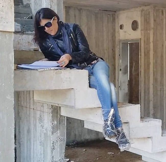 שרון אלה מעצבת פנים, בעת פיקוח שטח בתהליך בניה בקיבוץ געש, יושבת על מדרגות הבטון היצוק
