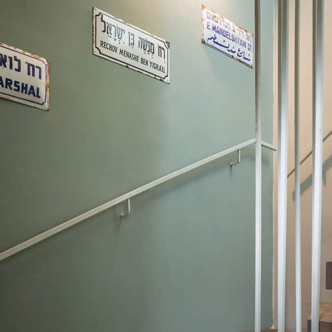 שלטי רחוב ישנים וינטג' על רקע קיר ירוק אפור במהלך מדרגות בדירת גג בתל אביב בעיצוב שרון אלה